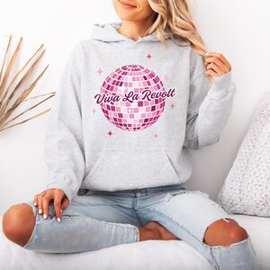 May include: A gray hoodie with a pink disco ball graphic and the text "Viva La Revolt" in pink.