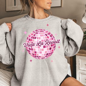 May include: Gray sweatshirt with a pink disco ball graphic and the text "Viva La Revolt" in pink.