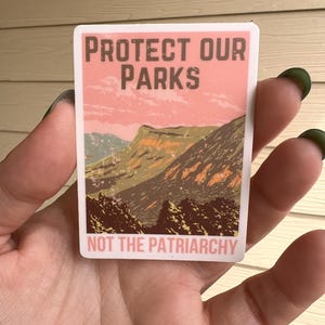 May include: A sticker with a pink and green mountain landscape and the text "Protect Our Parks Not The Patriarchy".