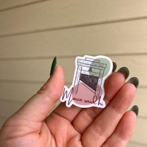 May include: A sticker with a drawing of a guillotine and the text "Marie said hi" in a cursive font.