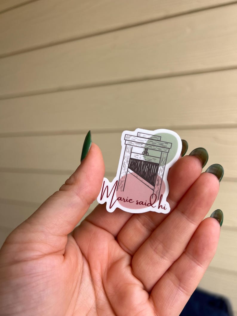May include: A sticker with a drawing of a guillotine and the text "Marie said hi" in a cursive font.