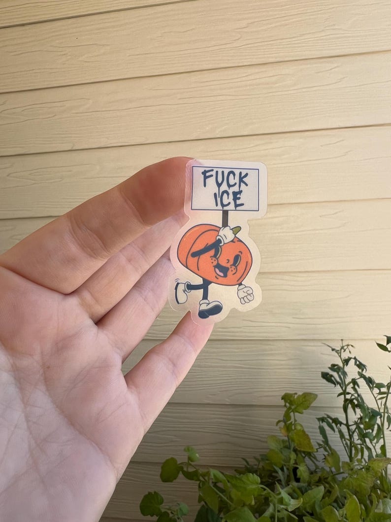 May include: A clear sticker featuring a cartoon pumpkin character holding a sign that reads "FUCK ICE". The pumpkin is orange with a smiling face, black shoes, and white gloves. The sign is white with black text.