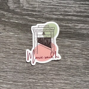 May include: A sticker with a black and white illustration of a guillotine with the text "Marie said hi" in pink and green.