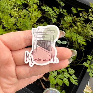 May include: A sticker with a drawing of a guillotine and the text "Marie said hi" in pink cursive lettering.