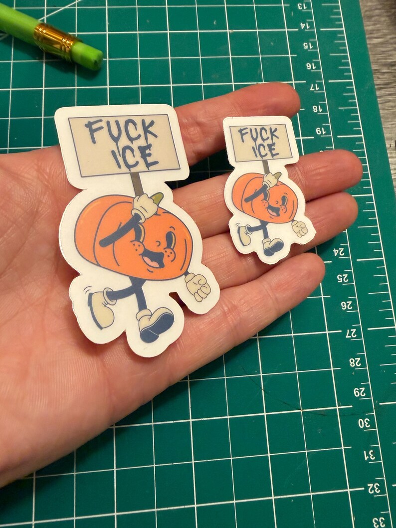 May include: Two die-cut stickers featuring an orange cartoon pumpkin character with a smiling face, arms, and legs. The pumpkin holds a rectangular sign above its head with the text FUCK ICE written in black capital letters on a light background.
