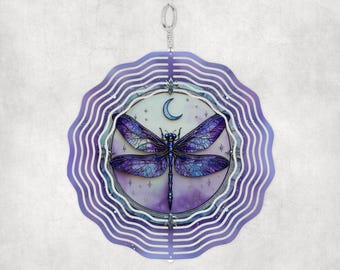 May include: Purple and blue metal wind spinner with a dragonfly and crescent moon design. The spinner has multiple layers of metal that spin in the wind.