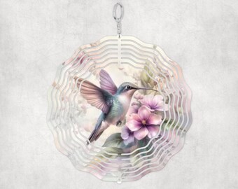 Puede incluir: Un molinillo de viento de metal con un diseño de colibrí y flores. El colibrí es azul, morado y rosa, y las flores son rosas y blancas. El molinillo de viento es plateado y tiene una forma circular.