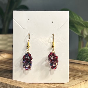 Peut inclure: Une paire de boucles d'oreilles pendantes avec un crochet dor&eacute; et un groupe de perles de cristal rouge.