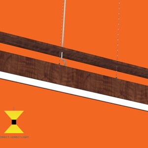 May include: A modern, rectangular pendant light fixture with a wood frame and a white LED light panel. The light is suspended from the ceiling by two thin wires. The fixture is made in the USA.  Direct / Direct Light.