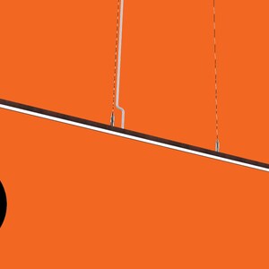 May include: A long, thin, black pendant light fixture hangs from the ceiling. The light is suspended by two thin wires. The light fixture is angled slightly downward.