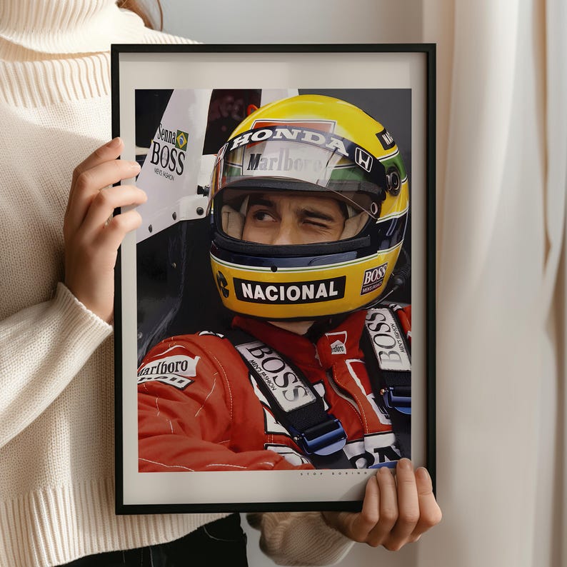 May include: A black and white photo of a race car driver wearing a yellow helmet with the word "HONDA" and "Marlboro" on it. The driver is wearing a red racing suit with the word "BOSS" on it. The photo is framed in a black frame.