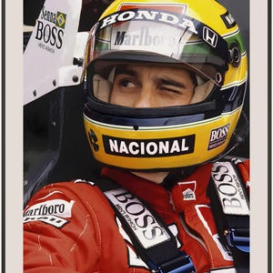 May include: A close-up of a race car driver wearing a yellow and blue helmet with the word "NACIONAL" on the front. The driver is wearing a red racing suit with the word "BOSS" on the chest and shoulders. The driver is winking at the camera.