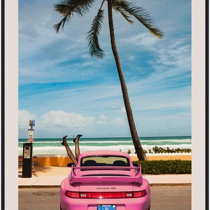 Puede incluir: Un Porsche Carrera 4S rosa estacionado en una carretera de playa con una palmera de fondo. Un par de piernas sobresalen por la ventana trasera del coche. El texto "STOP BORING WALLS" est&aacute; impreso debajo del coche.