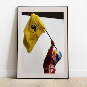 Può includere: Un pilota di auto da corsa con una tuta da corsa rossa agita una bandiera gialla con un logo Ferrari nero. La bandiera sventola nell'aria. Il pilota indossa un casco con un design blu, rosso e bianco. Il testo "Giancarlo Fisichella" è stampato nella parte inferiore dell'immagine.