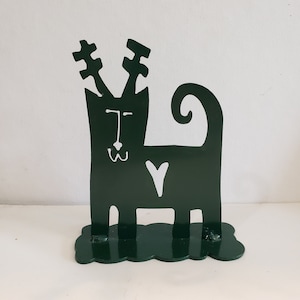 May include: A green metal silhouette of a cat with antlers, a heart, and a curly tail. The cat is standing on a green base.