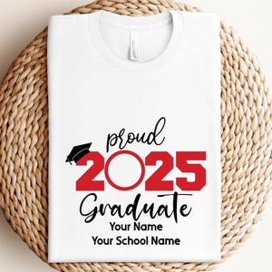 Pu&ograve; includere: Maglietta bianca con testo nero che dice "proud 2025 graduate" con un 2025 rosso. Il testo dice anche "Your Name" e "Your School Name".