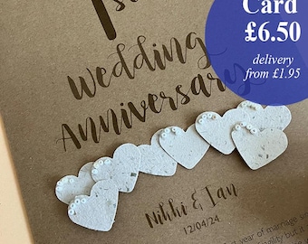 Puede incluir: Tarjeta marrón para el 1er aniversario de bodas, con el texto "on your 1st Wedding Anniversary". Presenta adornos de corazón de papel y los nombres "Nikki & Ian" con la fecha 12/04/24.