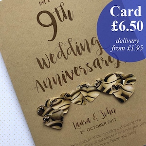 May include: A brown card for a 9th wedding anniversary. The card has the words "9th Wedding Anniversary" in a handwritten font. It features a string of heart-shaped decorations and the names "Laura & John" with the date "2nd October 2012".