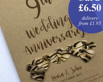 May include: A brown card for a 9th wedding anniversary. The card has the words "9th Wedding Anniversary" in a handwritten font. It features a string of heart-shaped decorations and the names "Laura & John" with the date "2nd October 2012".