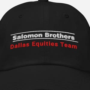 以下が含まれることがあります： 白で「Salomon Brothers」、赤で「Dallas Equities Team」と書かれた黒い野球帽。 つばがカーブしており、上部にボタンが付いています。 クラシックで調節可能な帽子です。