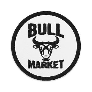 Puede incluir: Parche bordado circular con un toro negro y el texto "BULL MARKET". El diseño está centrado en un fondo blanco, enmarcado por un borde negro.