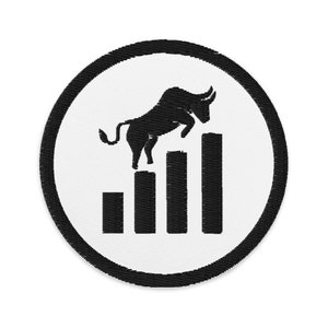 Puede incluir: Parche bordado con un toro negro saltando sobre gráficos de barras ascendentes, simbolizando el crecimiento del mercado. El diseño está sobre un fondo blanco dentro de un borde circular negro. Ideal para chaquetas, bolsos u otros artículos de tela.