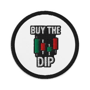 Puede incluir: Parche bordado con fondo blanco y borde negro. El parche presenta el texto "BUY THE DIP" en blanco, sobre un gráfico de gráficos de velas verdes y rojas.