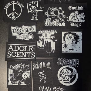 May include: A collection of black and white fabric patches featuring various band logos and graphic designs including War Lovers, Disrupt, Blitzkid, Icons of Filth, RKL, No Cash, English Dogs, Dogface Bastards, Adolescents, Wasted Youth, and others.