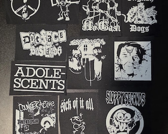 Puede incluir: Una colección de parches de tela en blanco y negro con varios logotipos de bandas y diseños gráficos, incluyendo War Lovers, Disrupt, Blitzkid, Icons of Filth, RKL, No Cash, English Dogs, Dogface Bastards, Adolescents, Wasted Youth y otros.