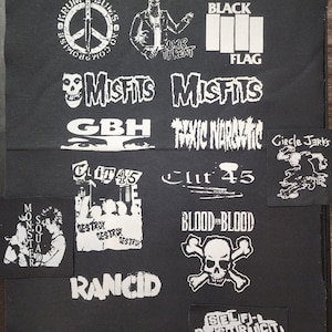 May include: A collection of white graphic patches on a black background. Patches feature band logos like "Misfits," "Black Flag," and "Rancid," along with other punk rock imagery, including skulls, peace signs, and text like "Blood for Blood."