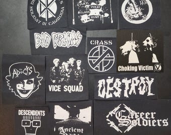 Può includere: Una collezione di dodici toppe in tessuto nero con grafiche e testo serigrafati in bianco, inclusi i nomi di band come Dead Kennedys, Bad Brains, Germs, Crass, Choking Victim, Adicts, Vice Squad, Descendents, Ancient Rage e Career Soldiers.