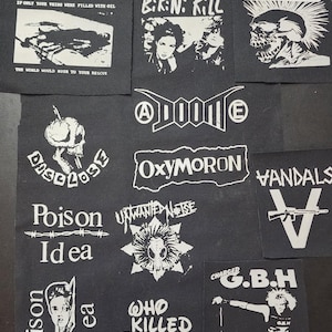May include: A collection of black and white punk rock patches featuring band names and graphics. Patches include "Minor Threat," "Aus-Rotten," "Bikini Kill," "The Exploited," "Doom," "Oxymoron," and "Vandals." The patches are square or rectangular.