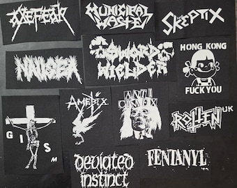 Può includere: Una collezione di toppe nere con testo e grafica bianchi. Le toppe presentano nomi di band come "Axefear", "Municipal Waste" e "Skeptix", insieme ad altri disegni e frasi. Le toppe sono rettangolari e di varie dimensioni.