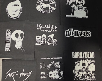 Puede incluir: Una colección de parches de tela negra con gráficos y texto serigrafiados en blanco, incluyendo nombres de bandas como X-Ray Spex, G.L.O.S.S., The Ejected, Ajax, Subhumans, The Die Hards, Born/Dead, Surf-Nazis Must Die y The Queers.