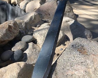 May include: A blue and silver sword with a decorative hilt, resting on a pile of rocks.