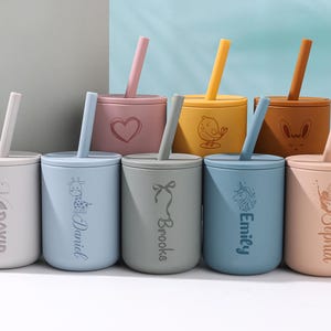 Puede incluir: Un juego de ocho tazas de silicona coloridas con pajitas, cada una con un diseño y un nombre diferentes. Las tazas son en tonos de blanco, azul claro, rosa, amarillo y marrón. Cada taza tiene un diseño diferente, incluyendo un corazón, un pájaro y un unicornio.