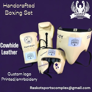 May include: A set of handcrafted boxing equipment made of cowhide leather. The set includes a pair of boxing gloves, a head guard, and a mouth guard. The equipment is cream colored with purple accents and features the text "Bletchley" and "Alhaq Sports Boxing".