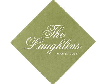 May include: A square sage green paper napkin oriented as a diamond. The napkin features white text in a decorative script font that reads The Laughlins, with the date MAY 5, 2026 printed below in a smaller, clean, sans-serif capital font.