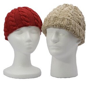 May include: Two knitted hats, one red and one beige, on white mannequin heads. The hats have a cable knit pattern.