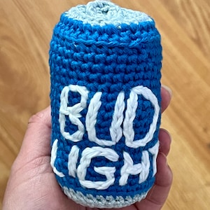 Puede incluir: Lata de crochet azul y blanca con el texto "BUD LIGHT" en ella.