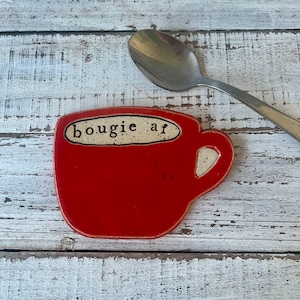 May include: Red ceramic mug shaped spoon rest with the text "bougie af" in white lettering.