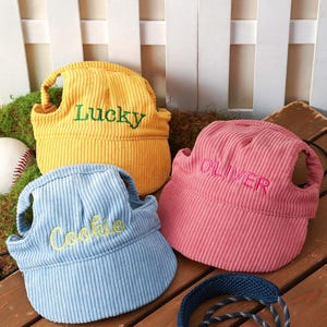 May include: Three corduroy pet hats in yellow, light blue, and pink. The yellow hat features the green embroidered text Lucky, the light blue hat has yellow embroidered text Cookie, and the pink hat has red embroidered text OLIVER.