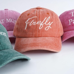 Puede incluir: Cuatro gorras de béisbol de diferentes colores con texto bordado. Las gorras son verde, rosa, naranja y rosa. El texto en las gorras dice "House Mom", "Great Mom", "Firefly" y "The Party".