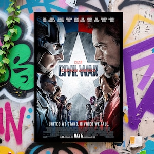 K&ouml;nnte beinhalten: Ein gerahmtes Filmplakat f&uuml;r Marvels "Captain America: Civil War". Das Poster zeigt Captain America und Iron Man einander gegen&uuml;ber, mit unterst&uuml;tzenden Charakteren auf beiden Seiten. Der Text "United We Stand. Divided We Fall" steht unten.