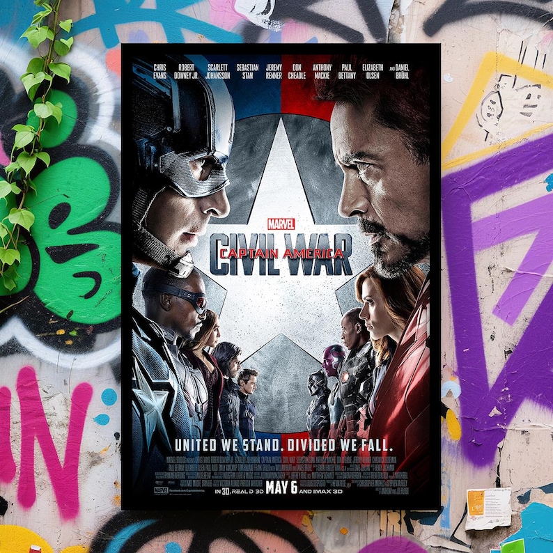 K&ouml;nnte beinhalten: Ein gerahmtes Filmplakat f&uuml;r Marvels "Captain America: Civil War". Das Poster zeigt Captain America und Iron Man einander gegen&uuml;ber, mit unterst&uuml;tzenden Charakteren auf beiden Seiten. Der Text "United We Stand. Divided We Fall" steht unten.