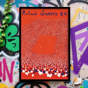 Może przedstawiać: Oprawiony wydruk artystyczny z napisem "Roland Garros 84" w kolorze niebieskim. Grafika ma czerwone tło z dużym czerwonym kwadratem i wzorem małych białych, czerwonych i niebieskich kropek. Rama jest czarna.