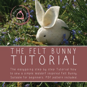 Puede incluir: Un conejito de fieltro blanco se sienta en un lecho de hierba verde y flores azules. El texto "THE FELT BUNNY TUTORIAL" se muestra en letras blancas sobre un fondo marrón. El texto debajo dice "The easygoing step by step Tutorial how to sew a simple Waldorf inspired Felt Bunny. Suitable for beginners. PDF pattern included."
