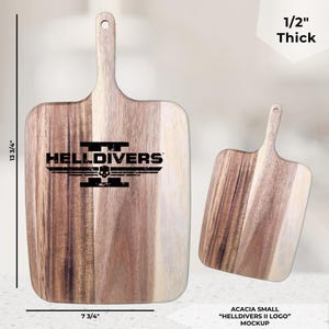May include: Two acacia wood cutting boards. The larger board is 13 3/4" long, 7 3/4" wide, and 1/2" thick, with a handle and the text "HELLDIVERS" and a logo. The smaller board is similar. The text "ACACIA SMALL 'HELLDIVERS II LOGO' MOCKUP" is also present.
