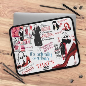 May include: A white laptop sleeve with a fashion-themed design. The design includes illustrations of women, high heels, handbags, and text such as "Fashion", "Cerulean", and "That's all". The sleeve is on a wooden surface.