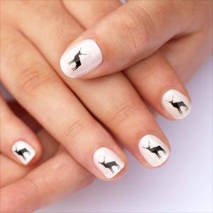 May include: Manicured nails with a white base and black deer silhouettes. The deer are depicted in a simple, stylized form, adding a touch of nature-inspired art to the nails. The design is clean and minimalist.